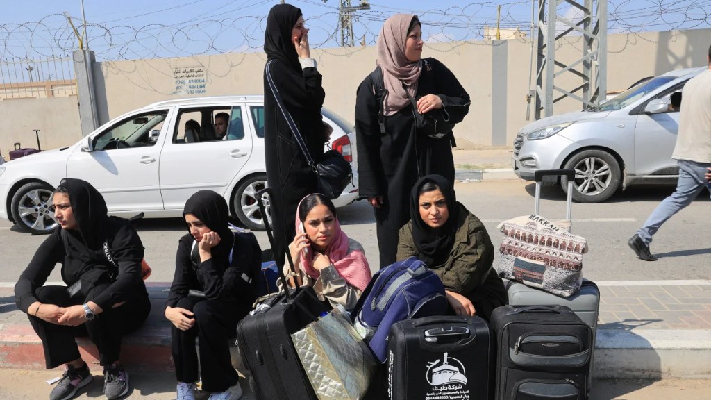 Personas con pasaportes extranjeros esperan en la puerta de Rafah con la esperanza de cruzar a Egipto mientras continúan los ataques de Israel contra la Franja de Gaza el 14 de octubre de 2023. (Said Khatib/AFP/Getty Images)