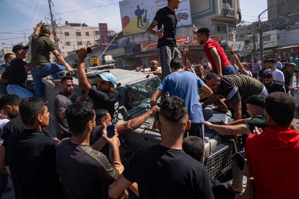 Palestinos se reúnen alrededor de un vehículo del ejército israelí que militantes palestinos condujeron desde Israel a Gaza el sábado. (Crédito: Fátima Shbair/AP)