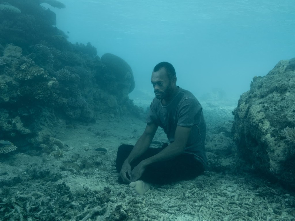 Qama se asienta en el fondo del océano, cubierto de trozos de coral roto.