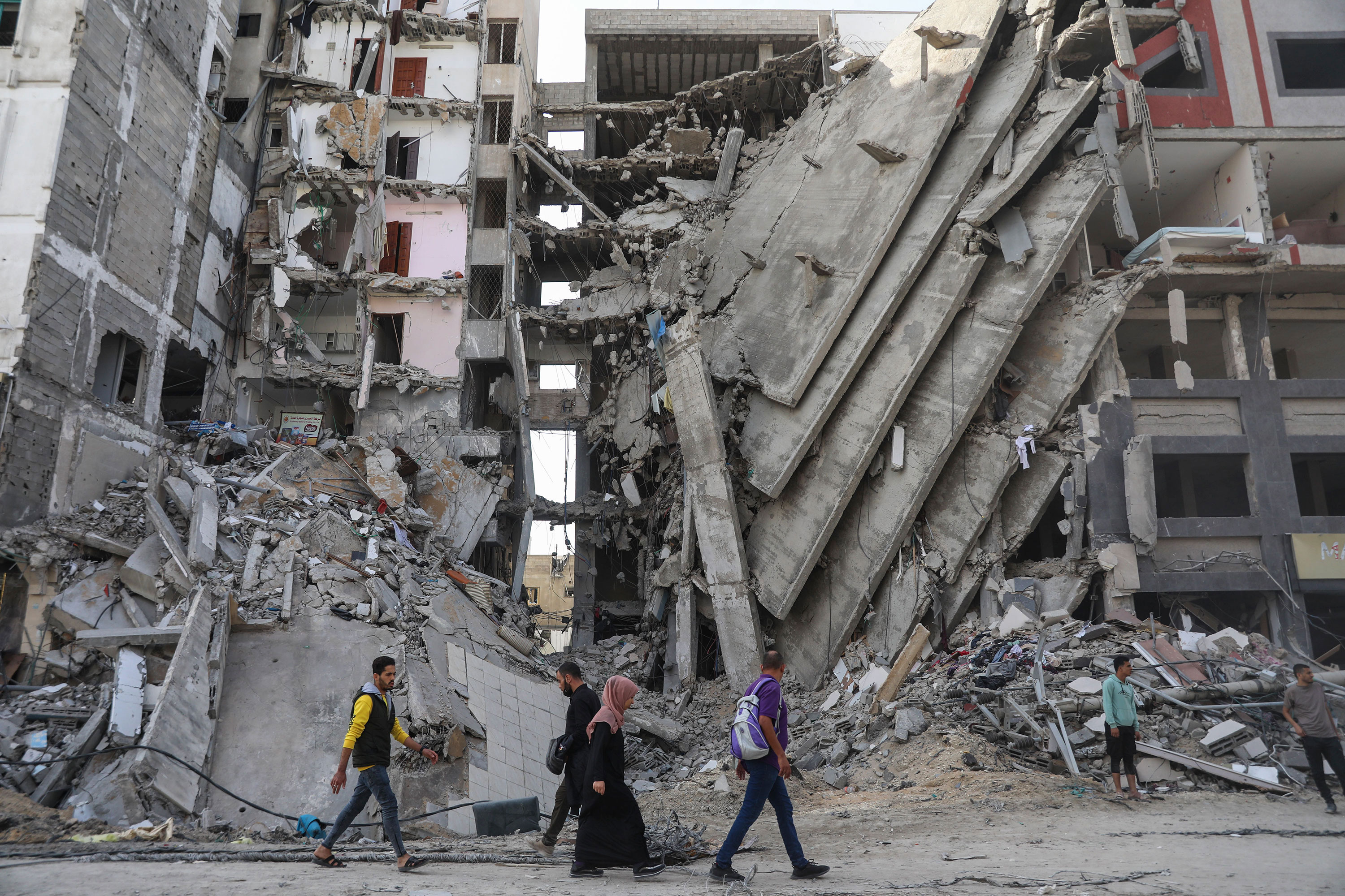 Palestinos caminan entre la destrucción en la ciudad de Gaza el 24 de noviembre, cuando entró en vigor la tregua temporal entre Israel y Hamás. (Crédito: Mohammed Hajjar/AP)