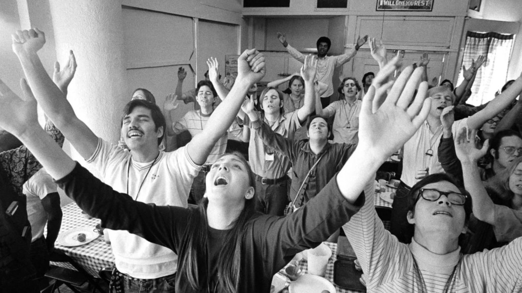Miembros de lo que alguna vez se llamó el Movimiento de Jesús cantan en un edificio de Los Ángeles en 1971. Ward dice que sus padres surgieron de un movimiento de cristianos durante esa década que estaban desencantados con la iglesia convencional. (Crédito: George Brich/AP)