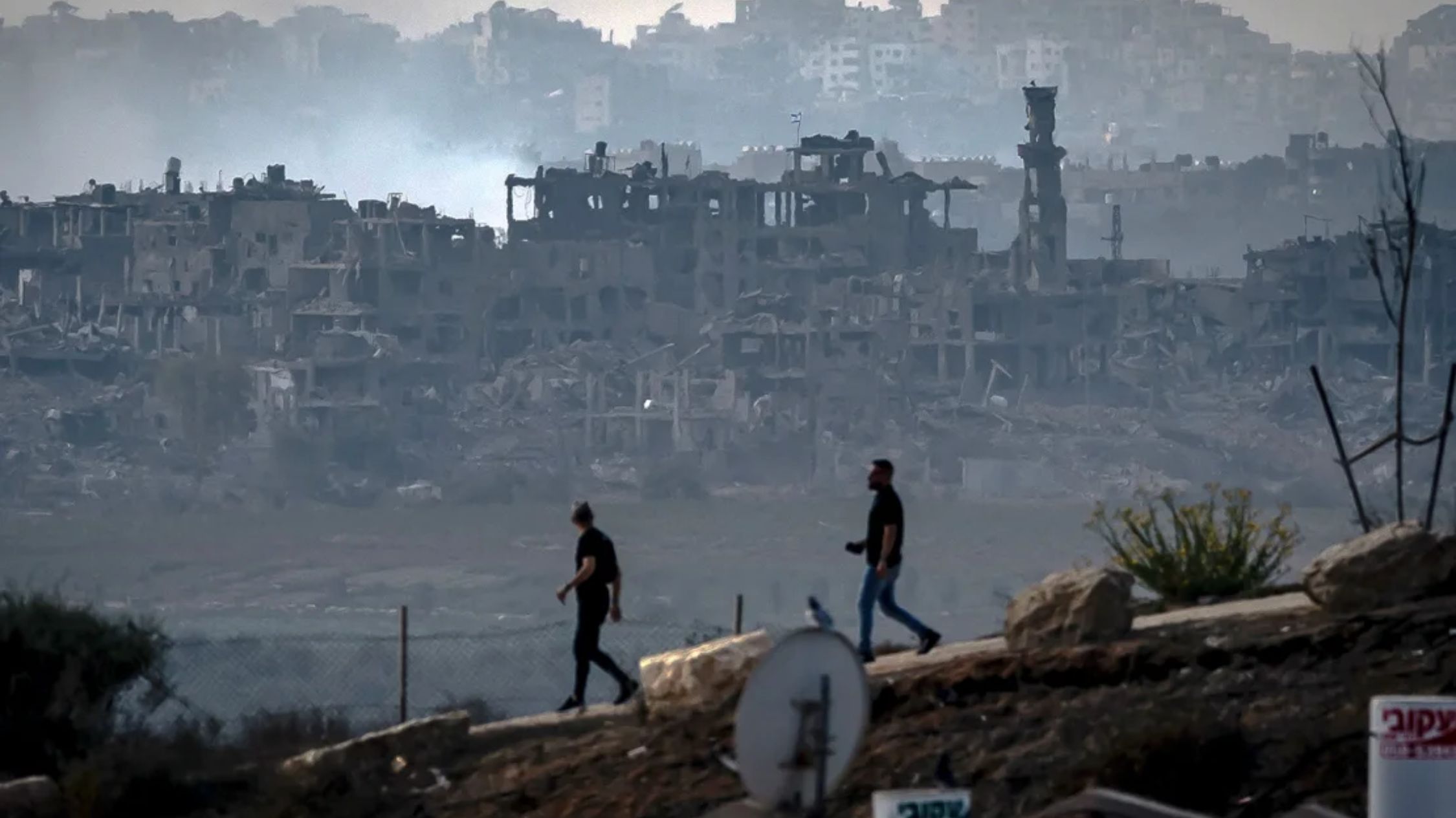 Hombres caminan a lo largo de la frontera de Gaza en el sur de Israel el 13 de noviembre de 2023. Zonas del territorio densamente poblado han sido objeto de implacables bombardeos israelíes. (Crédito: Fadel Senna/AFP/Getty Images)