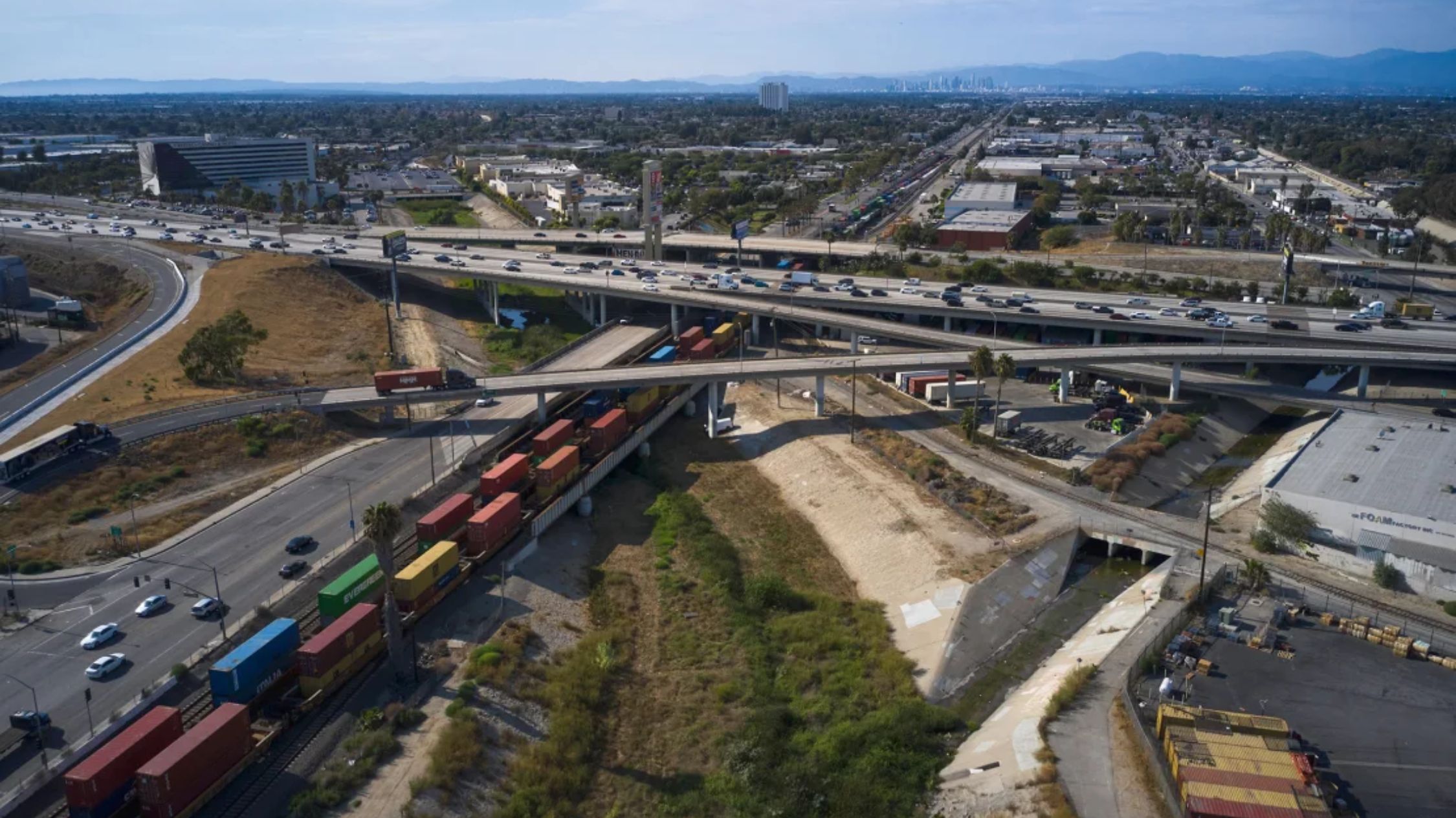 Una larga fila de contenedores de carga pasa bajo una carretera en Compton, California, EE.UU., el martes 2 de agosto de 2022. (Crédito: Bing Guan/Bloomberg/Getty Images)