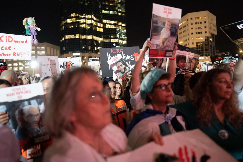 La gente se reúne y mira la pantalla grande mientras sostiene fotografías de rehenes en Tel Aviv, el 9 de noviembre de 2023. (Foto de DIMA VAZINOVICH/Middle East Images/AFP vía Getty Images)