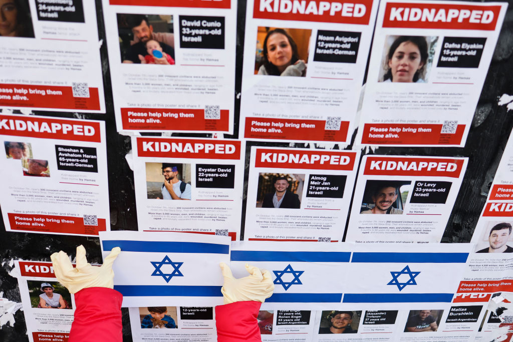  Personas sustituyen carteles con imágenes de rehenes israelíes en la esquina de la calle 23 con la Segunda Avenida el 30 de noviembre de 2023 en Nueva York. (Foto de Michael M. Santiago/Getty Images)