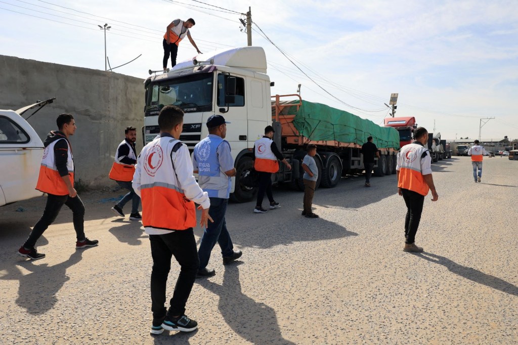 Trabajadores de la Media Luna Roja Palestina llegan para descargar camiones que transportan ayuda humanitaria que ingresaron a la Ciudad de Gaza desde Egipto a través del cruce fronterizo de Rafah el 21 de octubre de 2023. (SAID KHATIB/AFP via Getty Images)