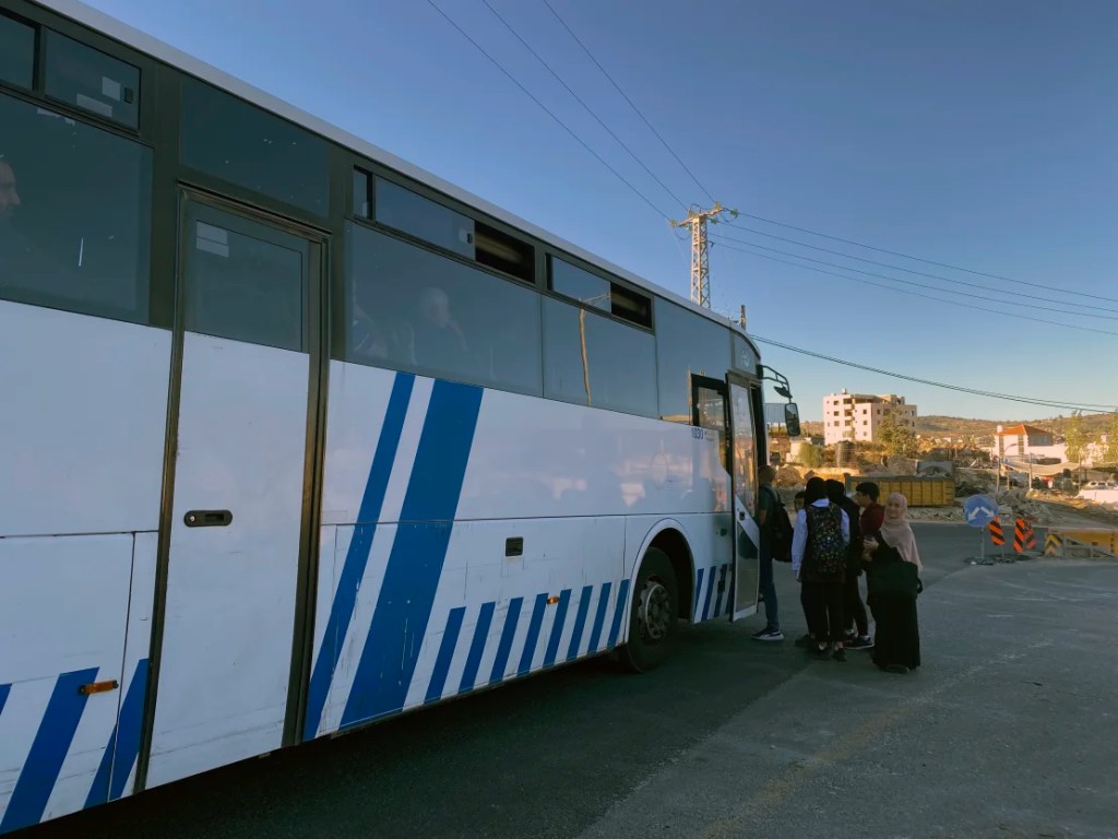 Un autobús que lleva a residentes de la Ribera Occidental a través de un puesto de control israelí hacia Jerusalén se detiene para recoger a los pasajeros que esperan al costado de la carretera, el lunes 6 de noviembre. 