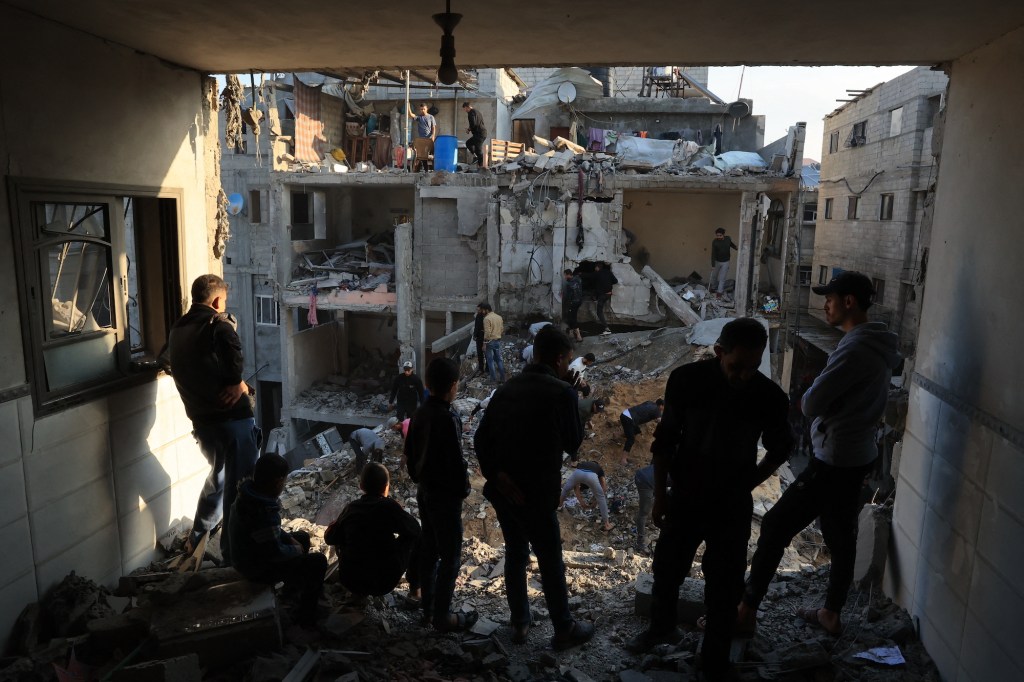 Palestinos inspeccionan la destrucción alrededor de edificios residenciales tras los ataques aéreos israelíes en el campo de refugiados de Rafah el viernes. (Said Khatib/AFP/Getty Images)