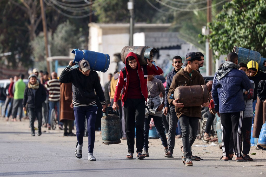 La gente lleva botes de gas vacíos para llenarlos con gas de cocina procedente de un tanque que entró en Gaza a través del cruce de Rafah con Egipto el sábado. (Dijo Khatib/AFP/Getty Images)