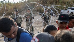 Soldados de la Guardia Nacional de Texas vigilan mientras los solicitantes de asilo esperan ser procesados ​​por agentes de la Patrulla Fronteriza de Estados Unidos después de cruzar de México a Estados Unidos el 30 de septiembre de 2023 en Eagle Pass, Texas. (Foto de John Moore/Getty Images)