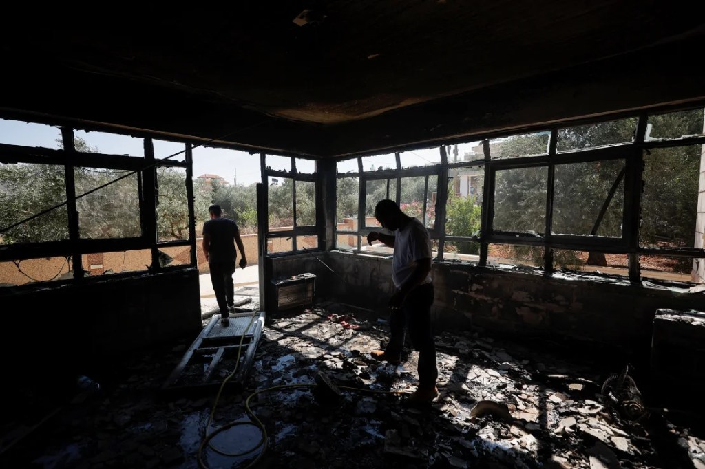 Hombres palestinos revisan un edificio quemado después de un ataque de colonos israelíes, cerca de Ramallah, en la Ribera Occidental ocupada por Israel, el 21 de junio de 2023. (Mohamad Torokman/Reuters)