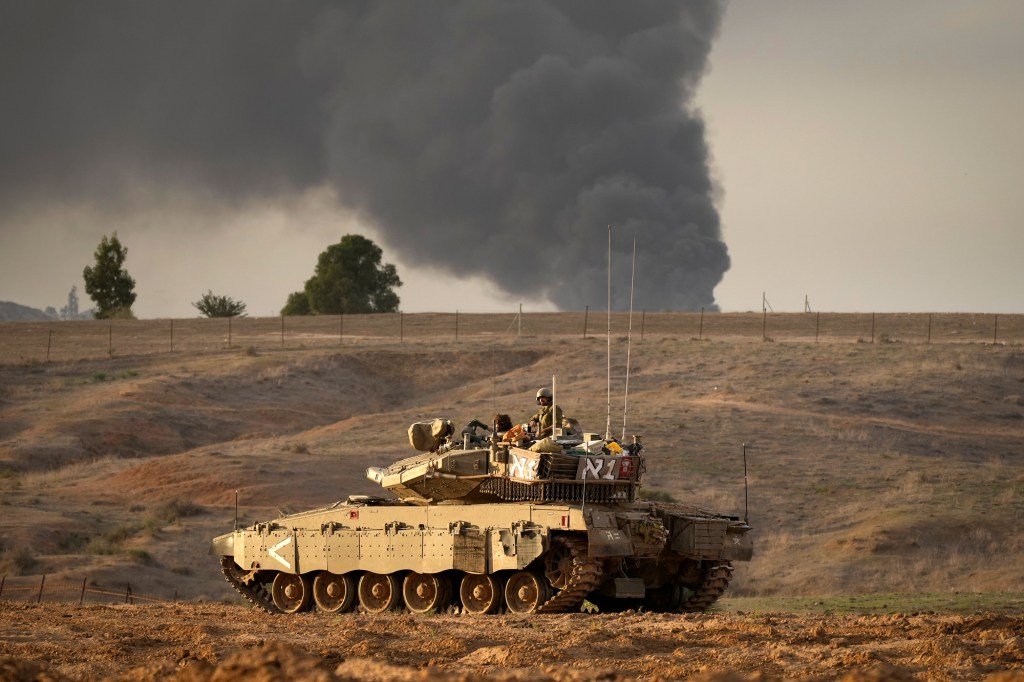 El humo de la Ciudad de Gaza llena el cielo a lo lejos mientras un tanque israelí se dirige hacia Gaza, el 22 de noviembre, en el sur de Israel. (Christopher Furlong/Getty Images)