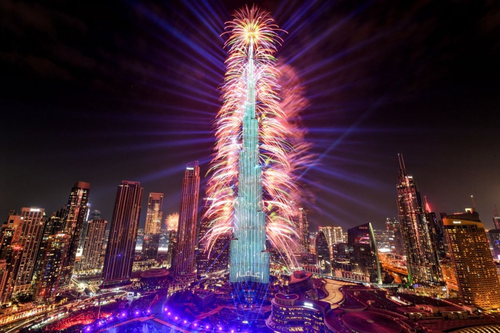 Los fuegos artificiales iluminan el cielo junto al emblemático rascacielos Burj Khalifa, el edificio más alto del mundo, en Dubai a la medianoche de la víspera de Año Nuevo el 1 de enero de 2024. (Foto de RYAN LIM/AFP vía Getty Images)