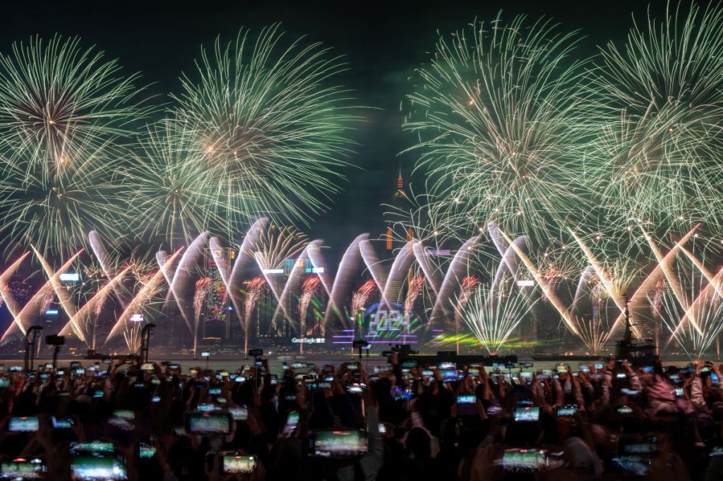 La gente observa la explosión de fuegos artificiales sobre el puerto de Victoria para marcar la llegada del año 2024 en Hong Kong, China, el 1 de enero de 2024. (Foto de Vernon Yuen/NurPhoto vía Getty Images)