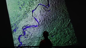 Un visitante observa un fragmento de una imagen por satélite del río Yukón, en Alaska, en la instalación artística "Passage of Water" de Yiyun Kang en el séptimo día de la Conferencia sobre el Clima COP28 de la CMNUCC en Expo City Dubai, el 6 de diciembre de 2023 en Dubai, Emiratos Árabes Unidos. (Crédito: Sean Gallup/Getty Images)