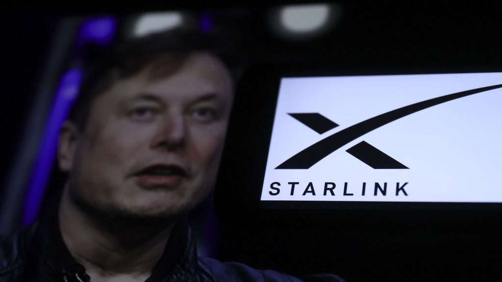 A Starlink logo on a screen next to a photo of Elon Musk (Credit: Ismail Aslandag/Anadolu via Getty Images)