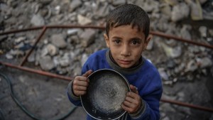 Un niño palestino sostenie una olla vacía mientras espera recibir alimentos distribuidos por voluntarios para familias palestinas desplazadas al sur de Gaza debido a los ataques israelíes, en Rafah, Gaza, el 22 de diciembre de 2023. (Abed Zagout/Anadolu via Getty Images)