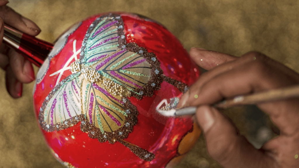Artesano pinta a mano una esfera de Navidad con diseño de mariposa. (Crédito: La Casa de Santa Claus)