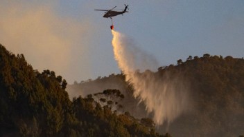 Un helicóptero de las Fuerzas Armadas arroja agua para apagar un incendio forestal en Bogotá el 23 de enero de 2024. (Crédito: LUIS ACOSTA/AFP vía Getty Images)
