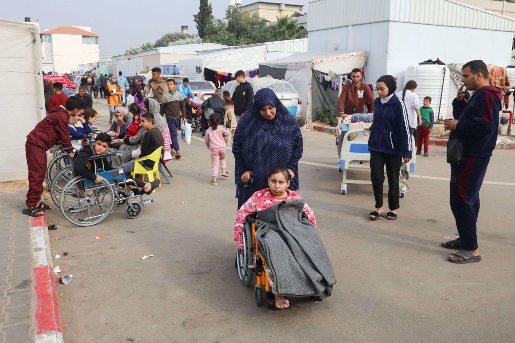 Noor Marouf, cuya extremidad fue amputada tras ser herida en un ataque israelí, está sentada en una silla de ruedas mientras su tía la ayuda en el Hospital Europeo de Rafah, Gaza, el 28 de diciembre. (Arafat Barbakh/Reuters)