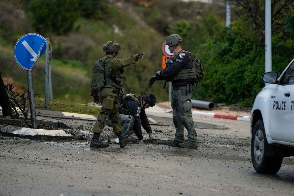 Las fuerzas de seguridad israelíes examinan el jueves una carretera alcanzada por un cohete disparado desde el Líbano, en Kiryat Shmona, al norte de Israel. (Leo Correa/AP)