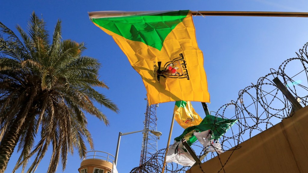 La bandera del grupo Kataib Hezbollah ondea en una protesta frente a la embajada de Estados Unidos en Bagdad, Irak, en 2019. (Thaier al-Sudani/Reuters/Archivo)