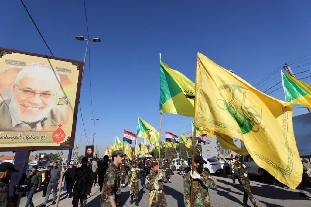 Los combatientes levantan banderas de Iraq y de grupos paramilitares, incluidos al-Nujaba y Kataib Hezbollah, durante un funeral en Bagdad por cinco militantes asesinados un día antes en un ataque estadounidense en el norte de Iraq, el 4 de diciembre de 2023. (AHMAD AL-RUBAYE/AFP via Getty Images)