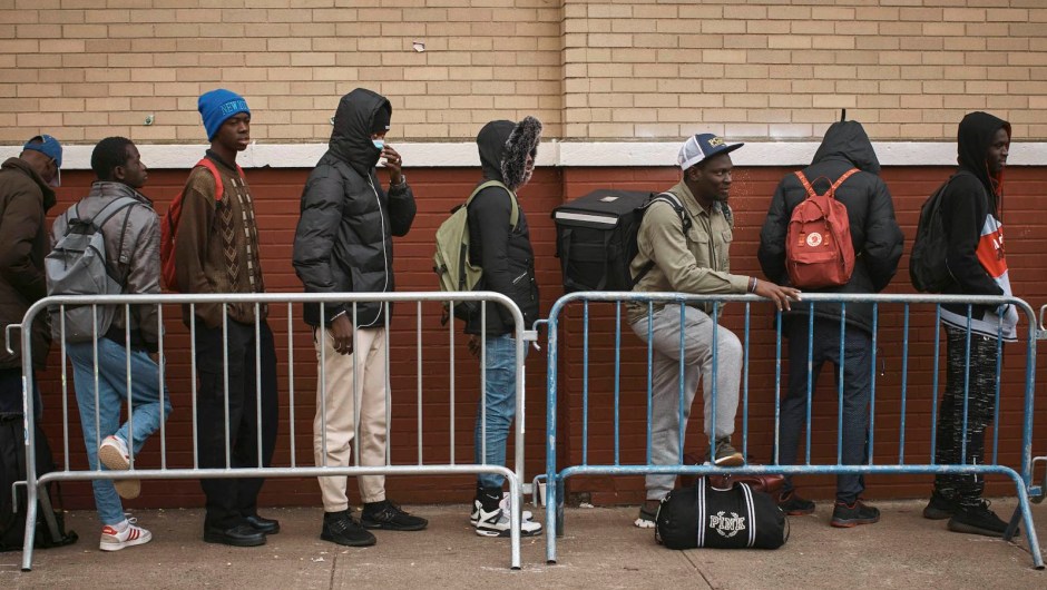 Migrantes hacen fila en el frío mientras buscan refugio afuera de un Centro de Asistencia a Migrantes en la Escuela Primaria St. Brigid el martes 5 de diciembre de 2023 en Nueva York. (Foto AP/Andrés Kudacki)