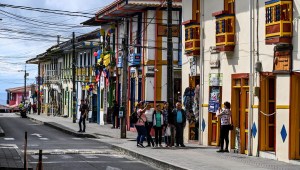 Turistas posan para una fotografía frente a coloridas tiendas en Filandia, departamento de Quindío, Colombia. (Foto de JUAN BARRETO/AFP vía Getty Images)