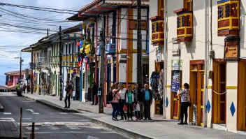 Turistas posan para una fotografía frente a coloridas tiendas en Filandia, departamento de Quindío, Colombia. (Foto de JUAN BARRETO/AFP vía Getty Images)