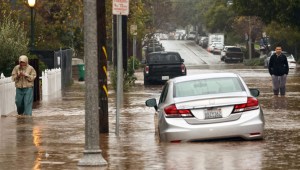 La gente se reúne a lo largo de una calle inundada mientras un poderoso río atmosférico de larga duración, la segunda en menos de una semana, impacta en California el 4 de febrero de 2024 en Santa Bárbara, California. (Crédito: Mario Tama/Getty Images)