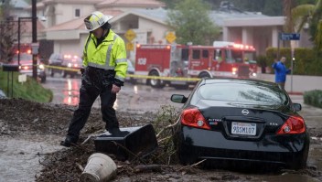 Un bombero camina cerca de un vehículo varado en lodo y rocas durante una tormenta en Los Ángeles el lunes. (Crédito: Eric Thayer/Bloomberg/Getty Images)