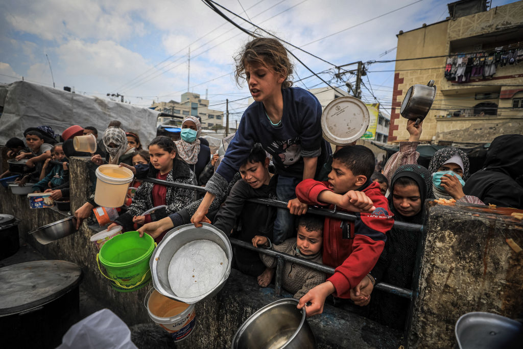 Palestinos desplazados se reúnen para recibir alimentos en un punto de donación en Rafah, en el sur de Gaza, el 24 de febrero de 2024. UNICEF, la Agencia de las Naciones Unidas para la Infancia y el Programa Mundial de Alimentos de las Naciones Unidas han advertido que los habitantes de Gaza se están acercando cada vez más a la hambruna. (Foto de Yasser Qudihe / Middle East Images / YASSER QUDIHE/AFP vía Getty Images).