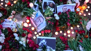 Retratos del líder opositor ruso, Alexey Navalny, flores y velas se colocan en el suelo mientras la gente protesta frente a la embajada de Rusia en Berlín el viernes. (Foto: Ebrahim Noroozi/AP).