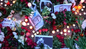 Retratos del líder opositor ruso, Alexey Navalny, flores y velas se colocan en el suelo mientras la gente protesta frente a la embajada de Rusia en Berlín el viernes. (Foto: Ebrahim Noroozi/AP).