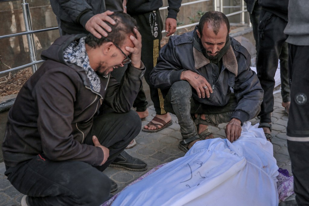 Personas en el hospital Al-Shifa en la ciudad de Gaza lloran por el cuerpo de un palestino muerto en medio de disparos israelíes y pánico en un punto de distribución de ayuda el 29 de febrero. (AFP/Getty Images)