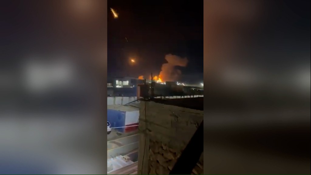 Una captura de pantalla de un video, geolocalizado por CNN en la ciudad de Qaim, Iraq, muestra las consecuencias de los ataques militares estadounidenses en la zona, según el ejército iraquí. Un aparente depósito de armas fue alcanzado y varias bengalas de proyectiles se dispararon hacia el cielo. (Crédito: CNN)