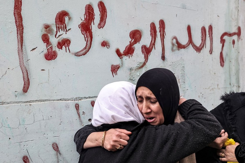 Una mujer consuela a la madre de Muhammad Ayman Ghazawi y Basel Ayman Ghazawi, dos de los tres palestinos que murieron cuando agentes israelíes encubiertos allanaron el hospital Ibn Sina en la ciudad de Yenín, en la Ribera Occidental. (Foto de ZAIN JAAFAR/AFP vía Getty Images)