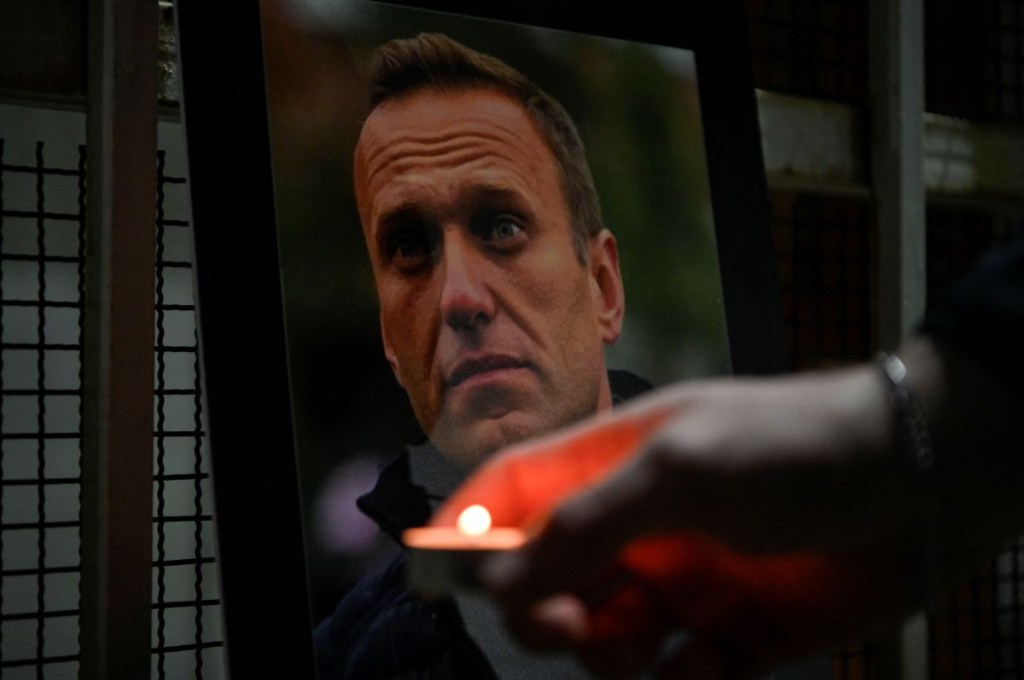 Una persona enciende una vela junto a un retrato del difunto líder de la oposición rusa Alexei Navalny, quien murió en una prisión rusa en el Ártico, colocado en la entrada de la Cancillería de la Embajada de la Federación Rusa en Pristina el 20 de febrero de 2024. (Foto por Armend NIMANI/AFP) (Foto de ARMEND NIMANI/AFP vía Getty Images)