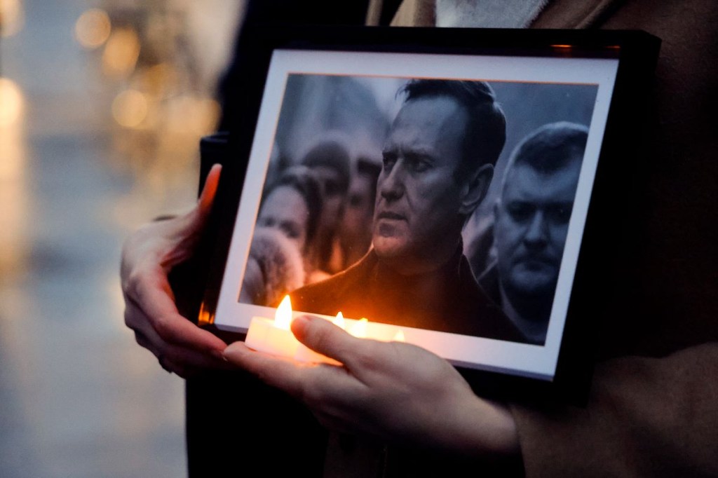 Un manifestante sostiene velas y una fotografía del difunto líder de la oposición Alexei Navalny, durante una manifestación organizada por la asociación 