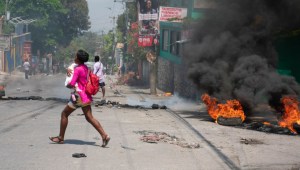 Una mujer con un niño en brazos huye de la zona tras escucharse disparos en Puerto Príncipe, Haití, el 20 de marzo de 2024. (Foto: CLARENS SIFFROY/AFP vía Getty Images)
