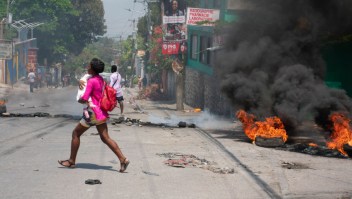 Una mujer con un niño en brazos huye de la zona tras escucharse disparos en Puerto Príncipe, Haití, el 20 de marzo de 2024. (Foto: CLARENS SIFFROY/AFP vía Getty Images)