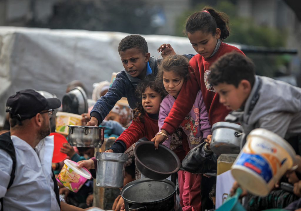 Palestinos desplazados se reúnen para recibir alimentos en un punto de donación en Rafah, en el sur de Gaza, el 24 de febrero de 2024. (Foto: Yasser Qudihe / Middle East Images/ AFP/vía Getty Images).