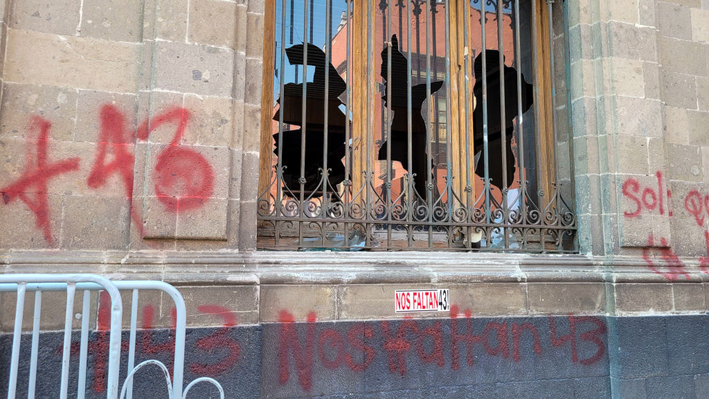 Vista de los cristales rotos de una ventana rota por manifestantes en el palacio presidencial de la Ciudad de México el 6 de marzo de 2024, durante una protesta por la desaparición de los 43 estudiantes de Ayotzinapa en 2014. (Foto: Ivan Castaneira/AFP vía Getty Images).