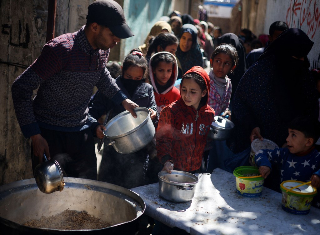 Niños palestinos esperan recibir comida cocinada en una cocina benéfica en medio de escasez de alimentos, en Rafah, Gaza, el 5 de marzo. (Mohammed Salem/Reuters)