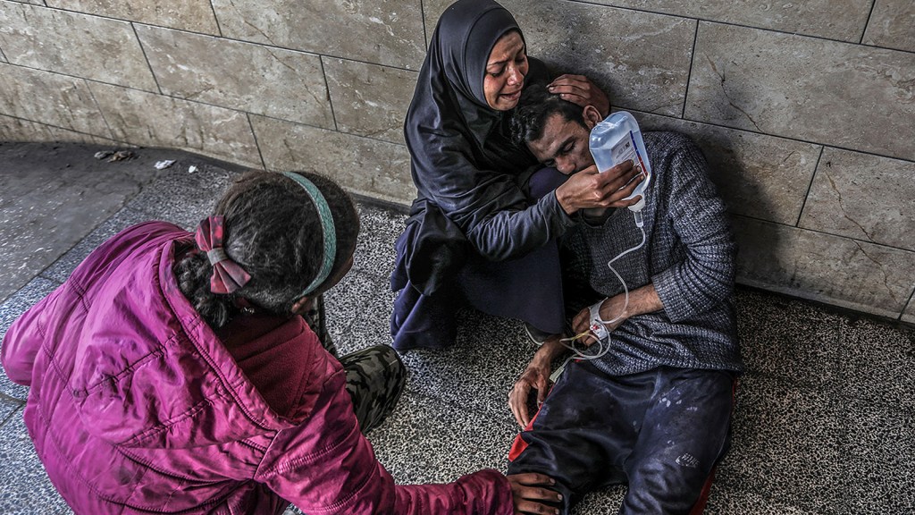 Una mujer palestina sostiene una solución de glucosa para su familiar, que resultó herido en un ataque aéreo israelí cerca de un almacén de la Agencia de Naciones Unidas para la población refugiada de Palestina en Oriente Próximo (UNRWA, por sus siglas en inglés), en el Hospital Al-Najjar en Rafah, Gaza. (Abed Rahim Khatib/picture-alliance/dpa/AP)