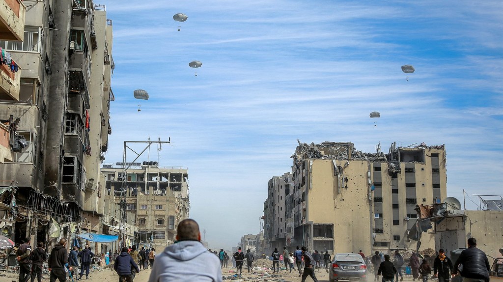 Los palestinos corren por una calle mientras se lanza ayuda humanitaria desde el aire en la ciudad de Gaza el 1 de marzo. (Foto: AFP/Getty Images).