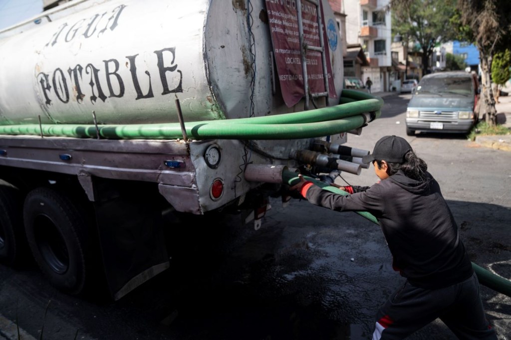 Un trabajador conecta una manguera a un camión cisterna afuera de un complejo de departamentos en el barrio Las Peñas en Iztapalapa el 27 de febrero de 2024 en Ciudad de México, México. (Foto de Toya Sarno Jordan/Getty Images)