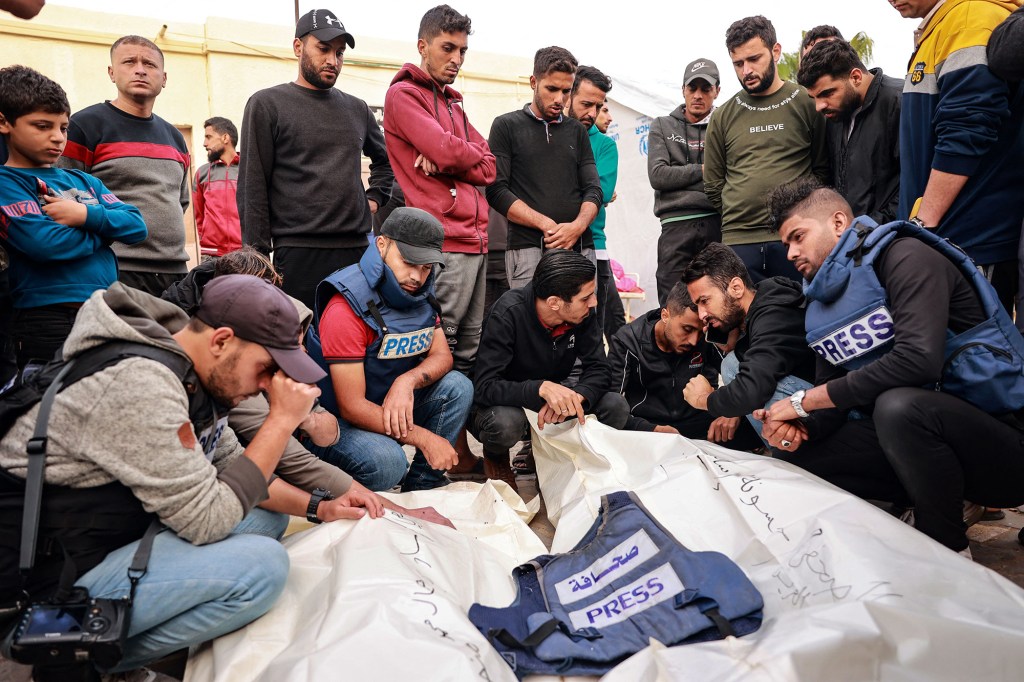 Amigos y colegas de dos periodistas palestinos Hasouna Slim y Sari Mansoor, muertos en un ataque israelí, lloran ante sus cuerpos durante su funeral en Deir al-Balah, en el sur de Gaza, el 19 de noviembre. (Foto: Bashar Taleb/AFP/GettyImages).