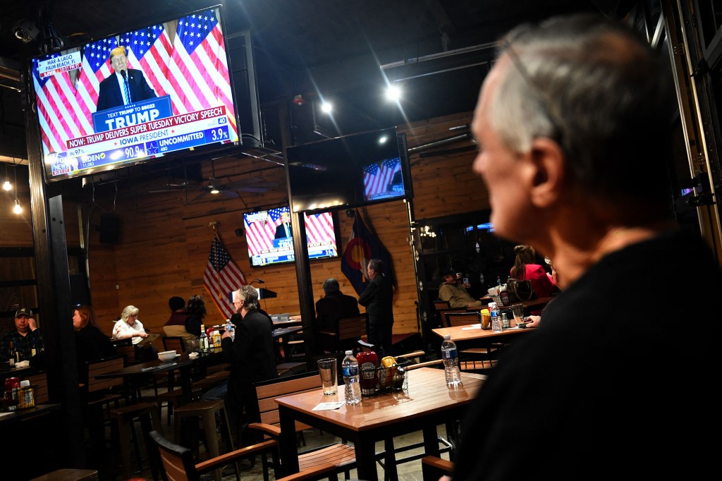 Un simpatizante del expresidente Donald Trump mira la transmisión de su discurso de victoria del supermartes durante una fiesta en el Wide Open Saloon en Sedalia, Colorado, el 5 de marzo. (Jason Connolly/AFP/Getty Images)